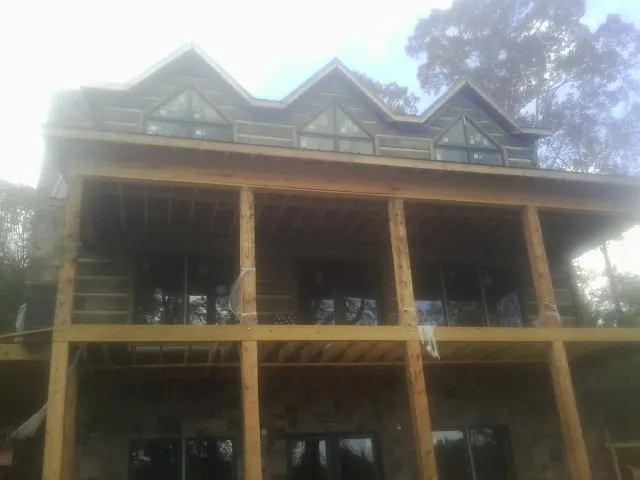 Dormers and porch framing on a large log home under construction — Roof Coating work by our crew in Northport